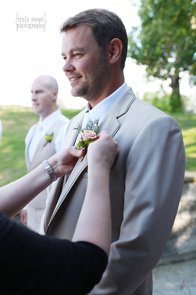 Groom getting flower pinned onto khaki suit